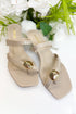 Beige sandals with gold accents on a white background