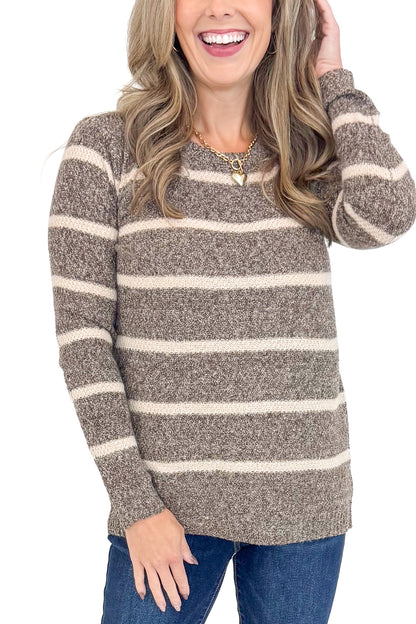 Front detailed view of woman wearing striped sweater with jeans against white studio background.