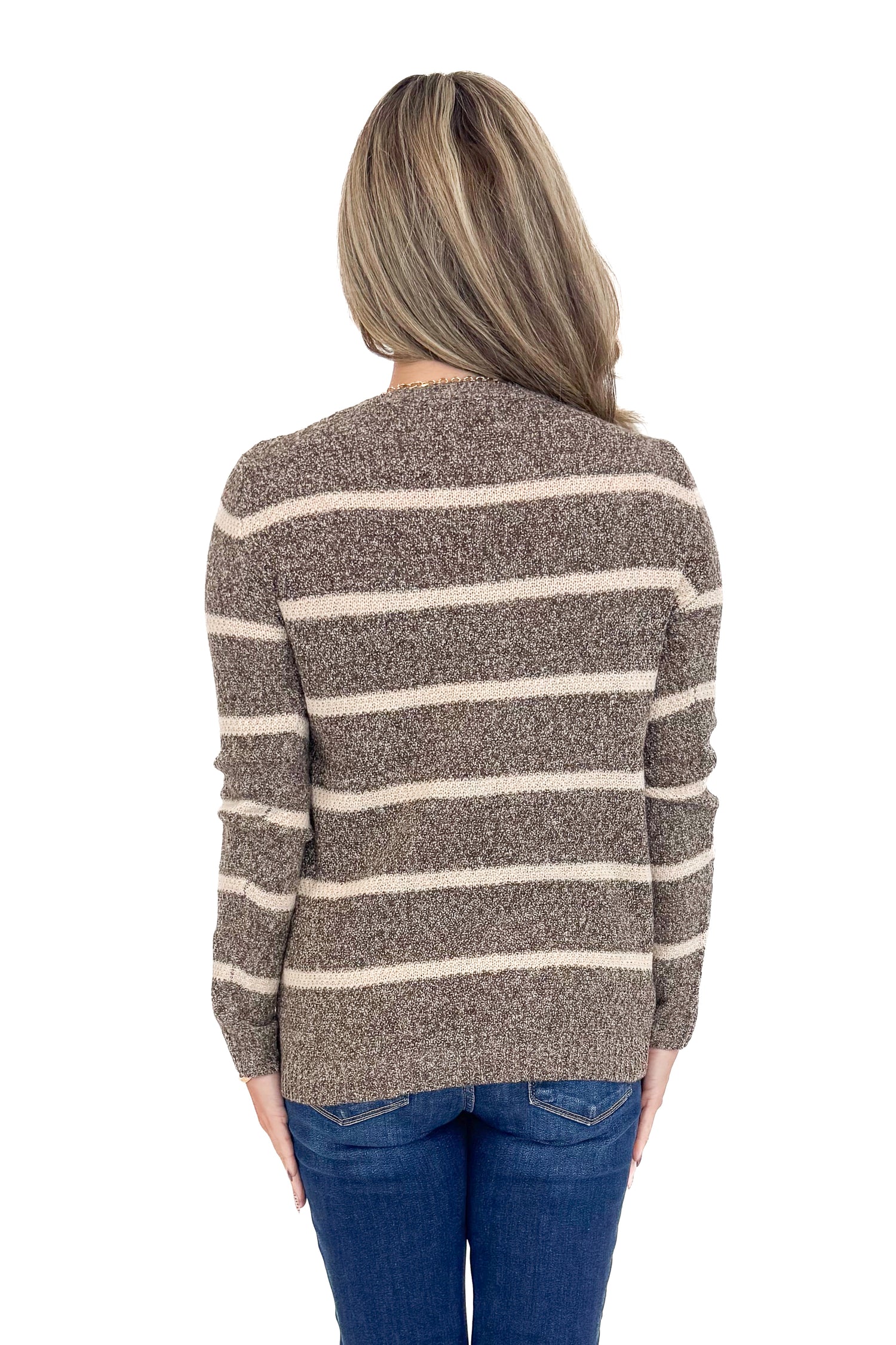 Rear view of woman wearing striped sweater with jeans against white studio background.