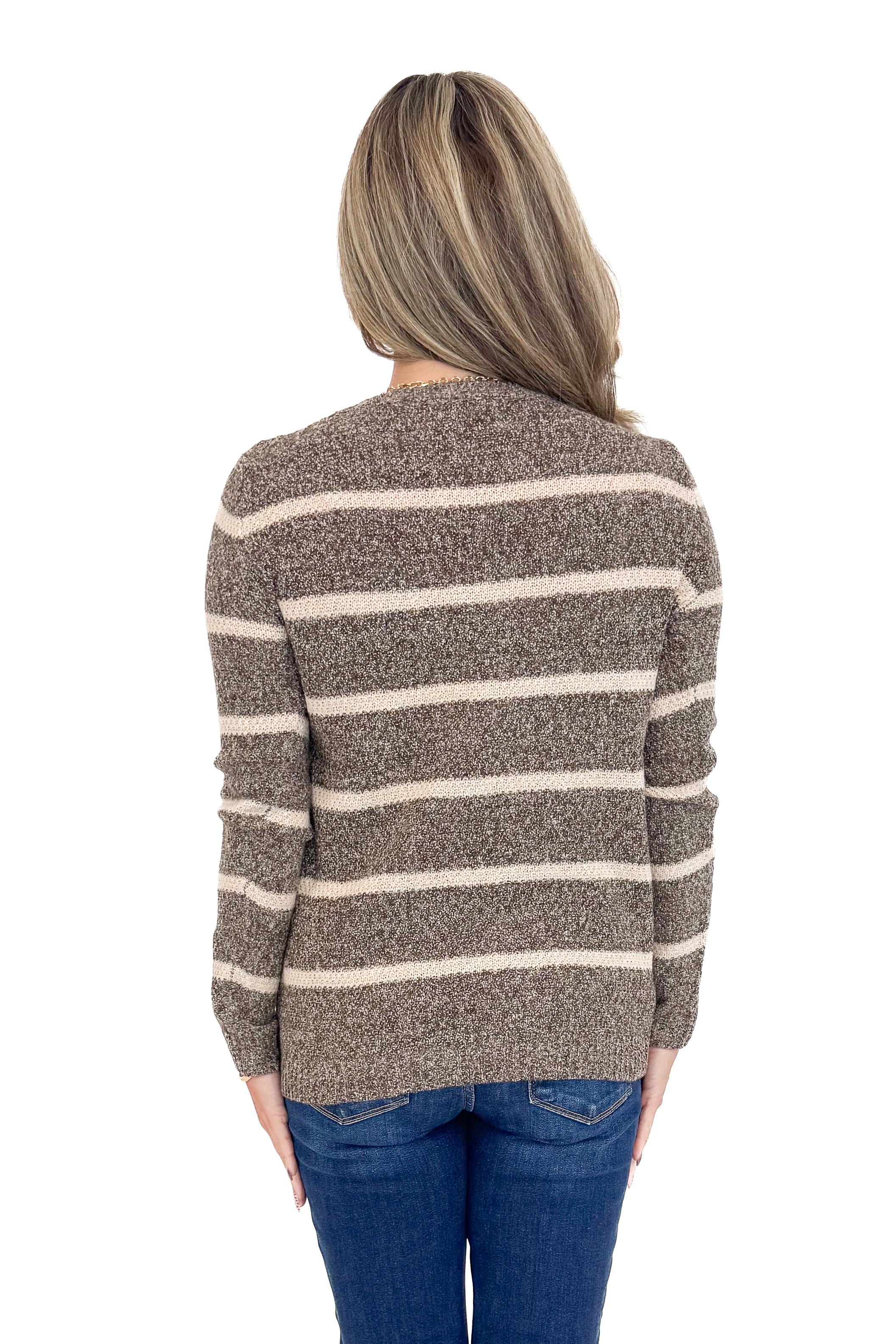 Rear view of woman wearing striped sweater with jeans against white studio background.
