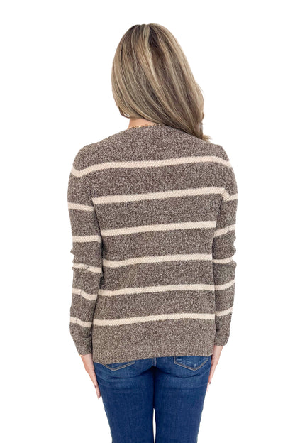 Rear view of woman wearing striped sweater with jeans against white studio background.