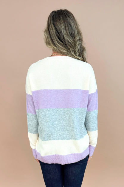 Back view of woman wearing Lavender &amp; Grey Colorblock Sweater and jeans with tan background.