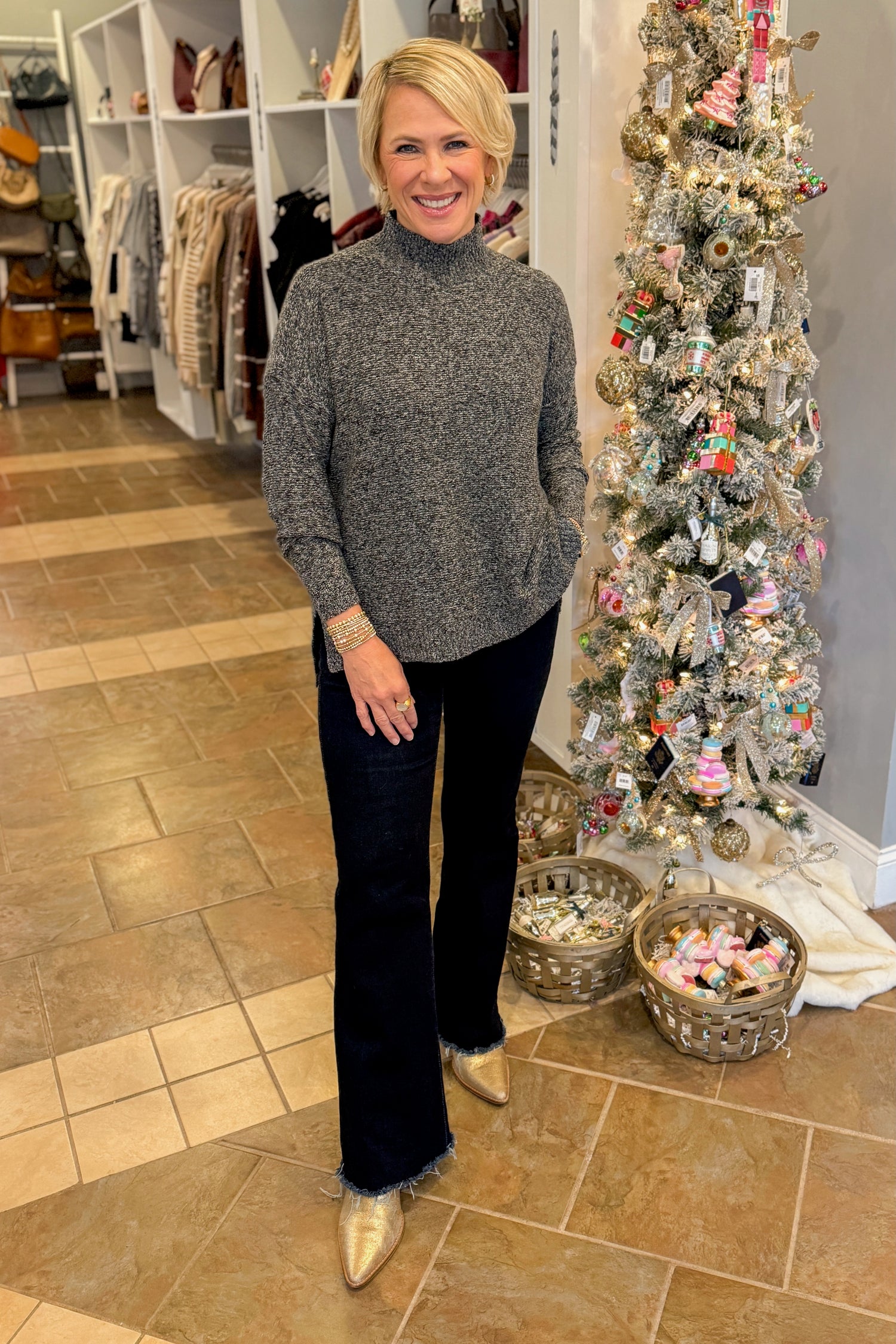 Front view of woman wearing Black &amp; Cream Marled Mock Neck Sweater with jeans against holiday decor.