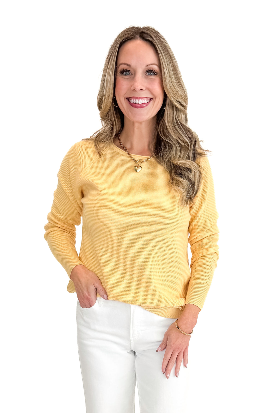 Front view of woman wearing Yellow Waffle Weave Sweater with jeans against a white background.