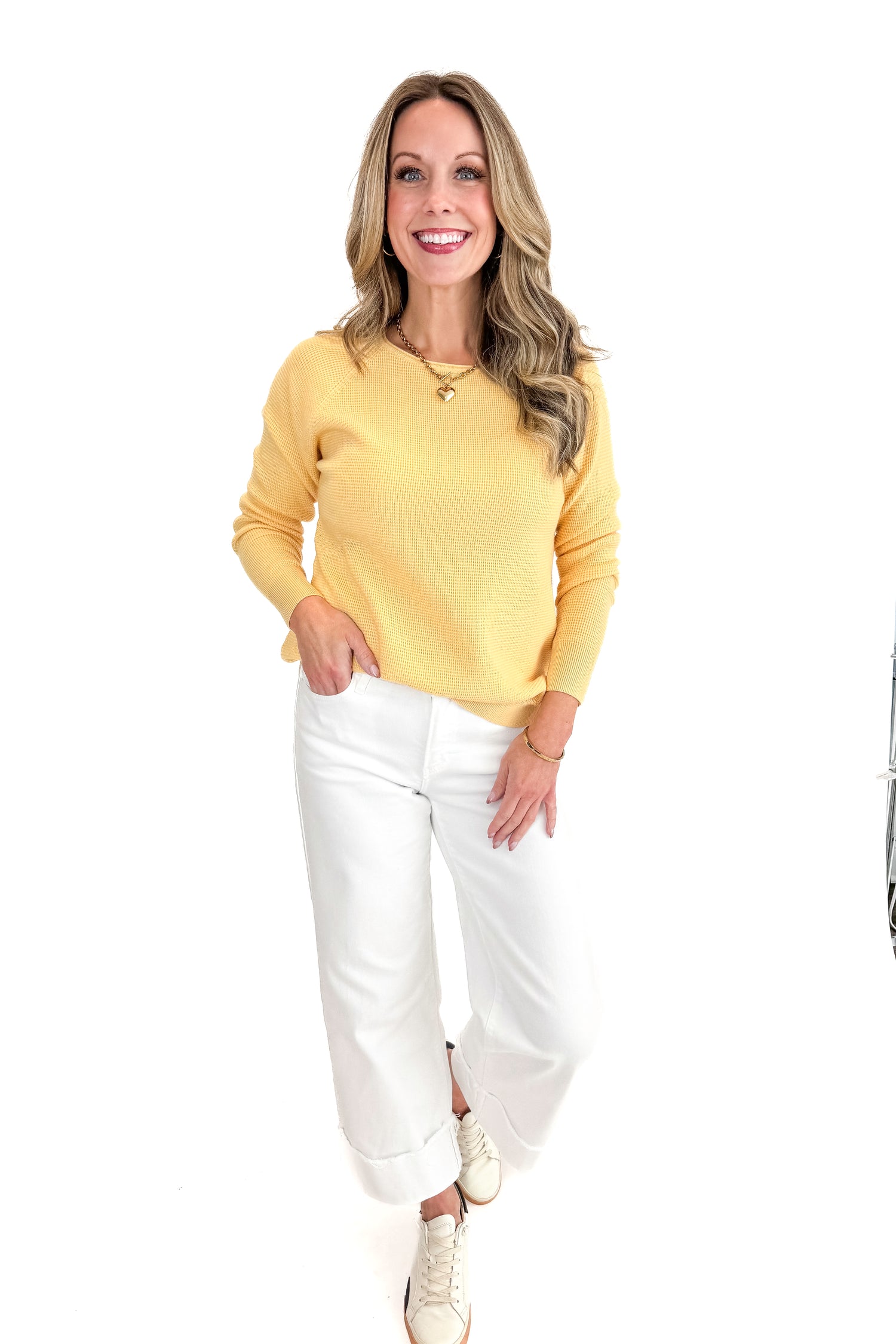 Front view of woman wearing Yellow Waffle Weave Sweater with jeans against a white background.