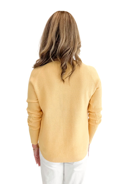 Back view of woman wearing Yellow Waffle Weave Sweater with jeans against a white background.