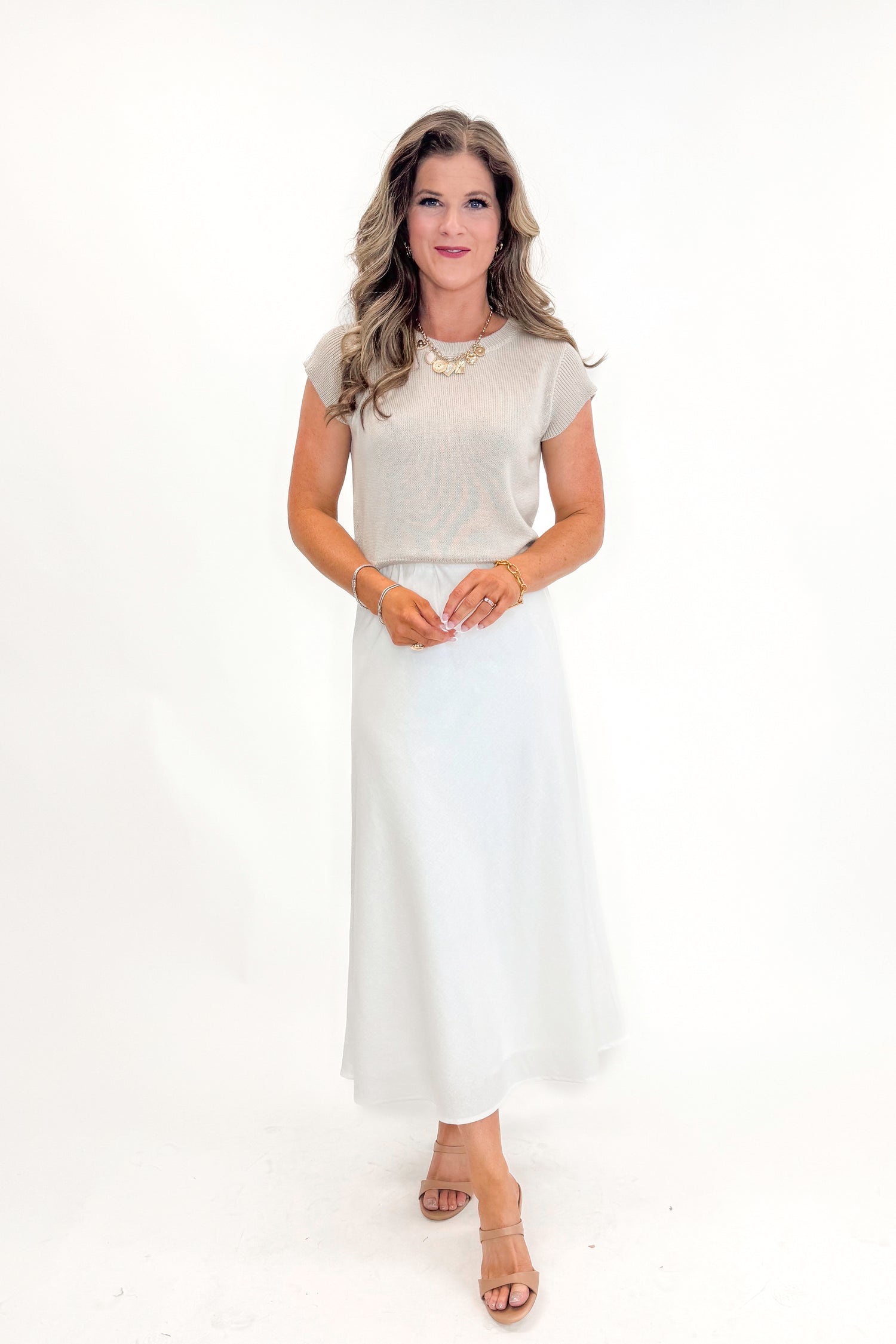 Front view of woman wearing Beige Cap Sleeve Sweater with skirt against white studio background.