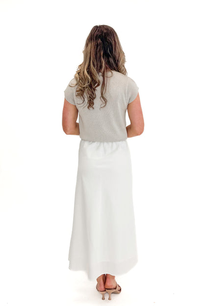 Back view of woman wearing Beige Cap Sleeve Sweater with skirt against white studio background.