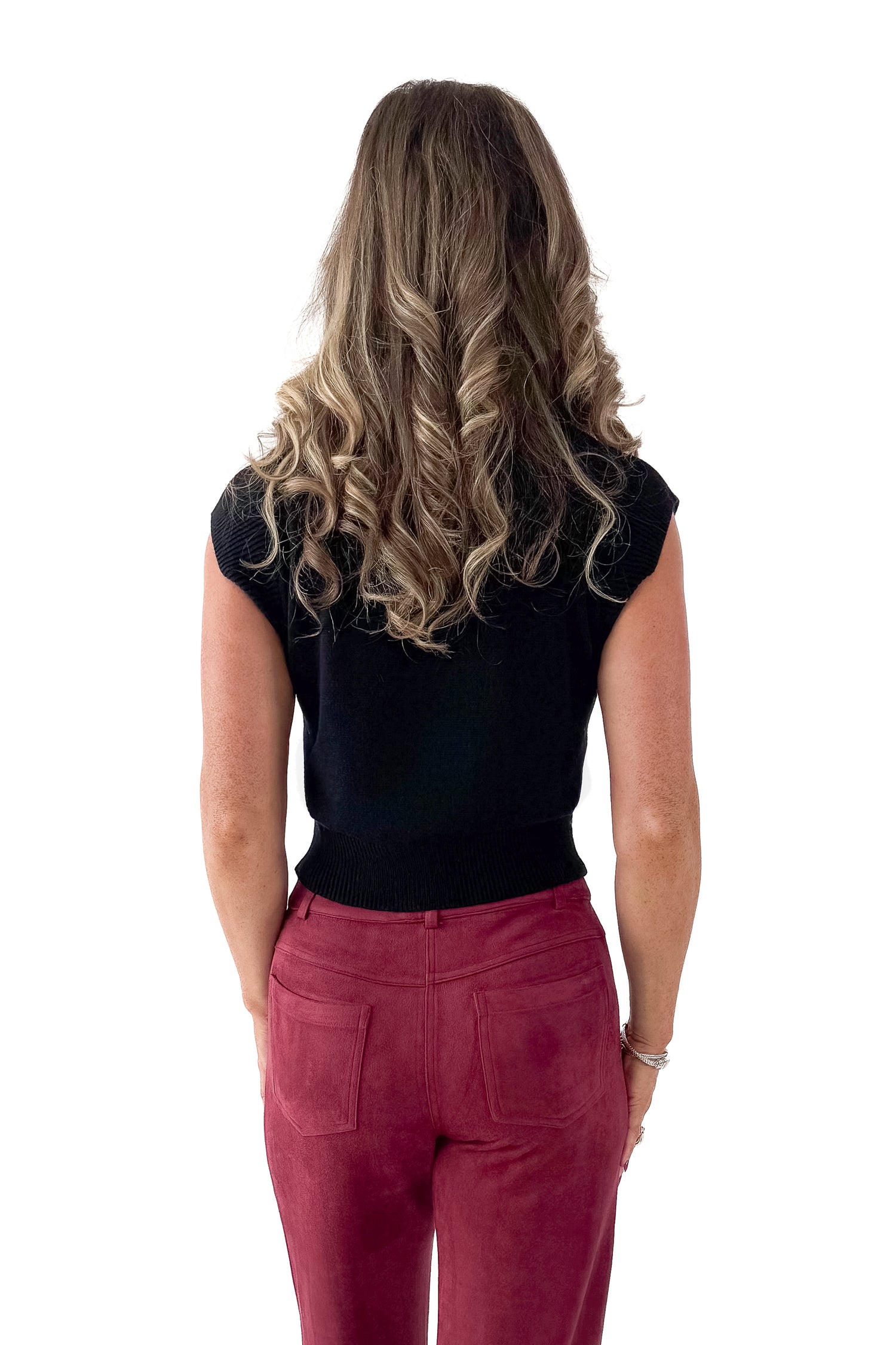 Back view of woman wearing Black Cap Sleeve Sweater with pants against white studio background.