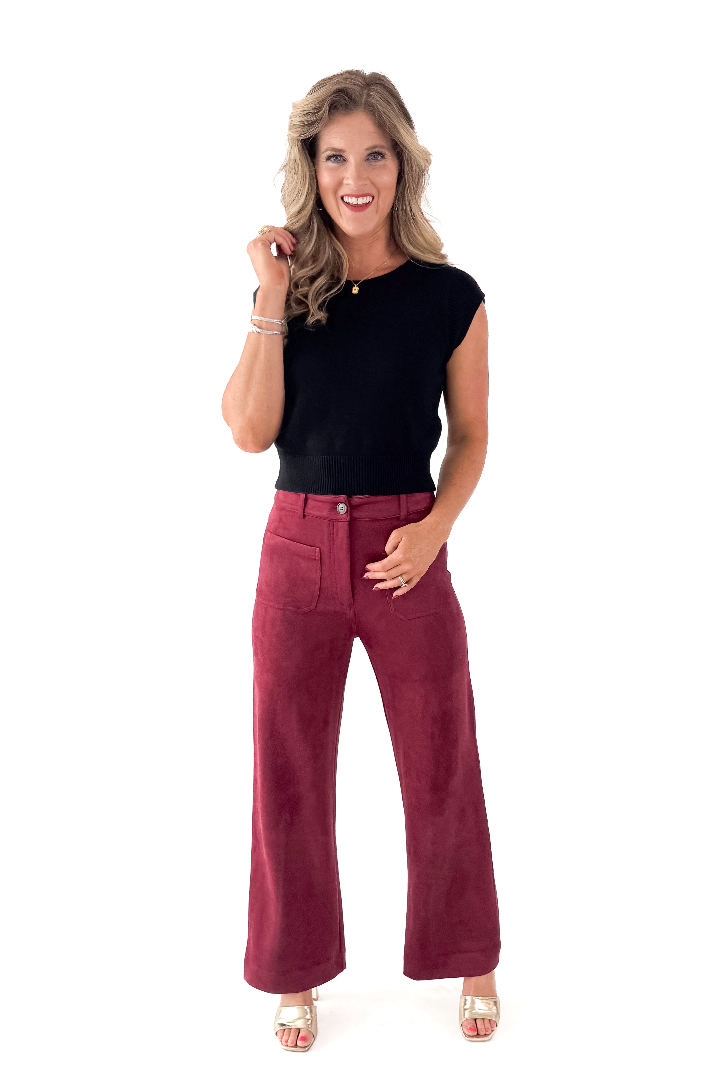 Front view of woman wearing Black Cap Sleeve Sweater with pants against white studio background.