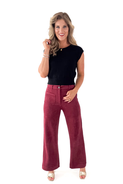 Front view of woman wearing Black Cap Sleeve Sweater with pants against white studio background.