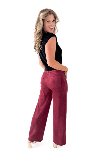 Side view of woman wearing Black Cap Sleeve Sweater with pants against white studio background.