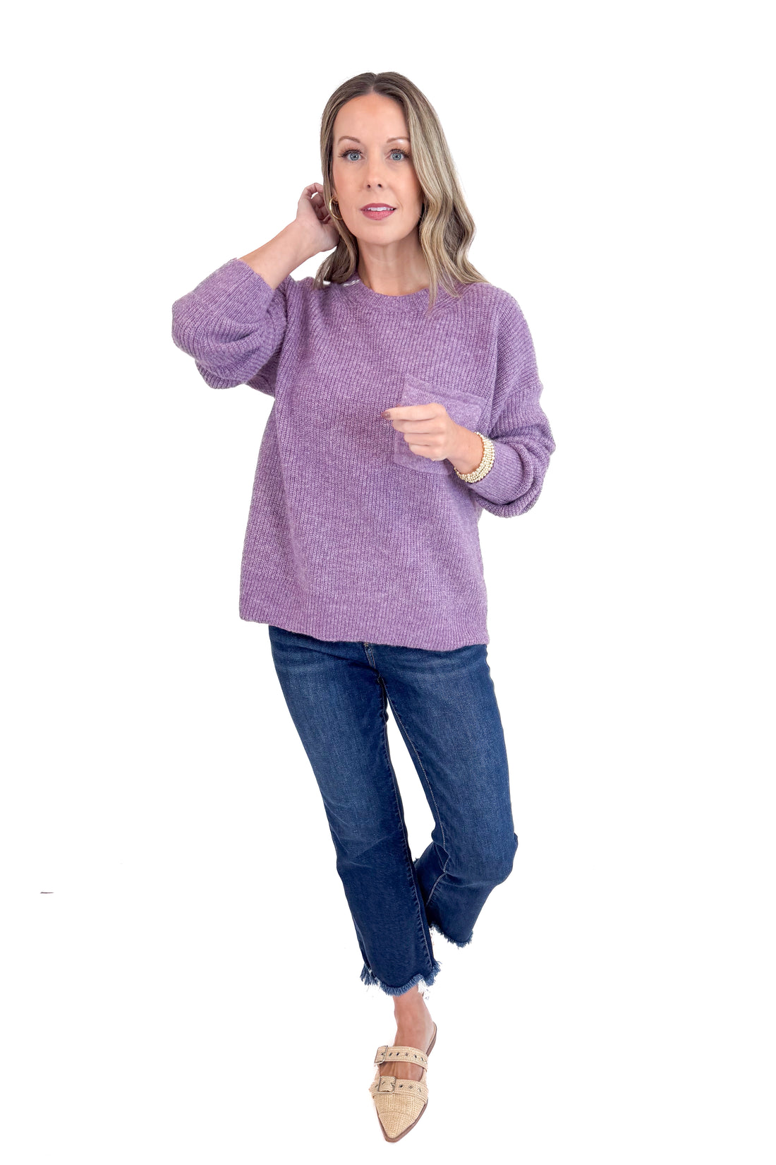 Woman wearing a purple sweater and blue jeans on a white background