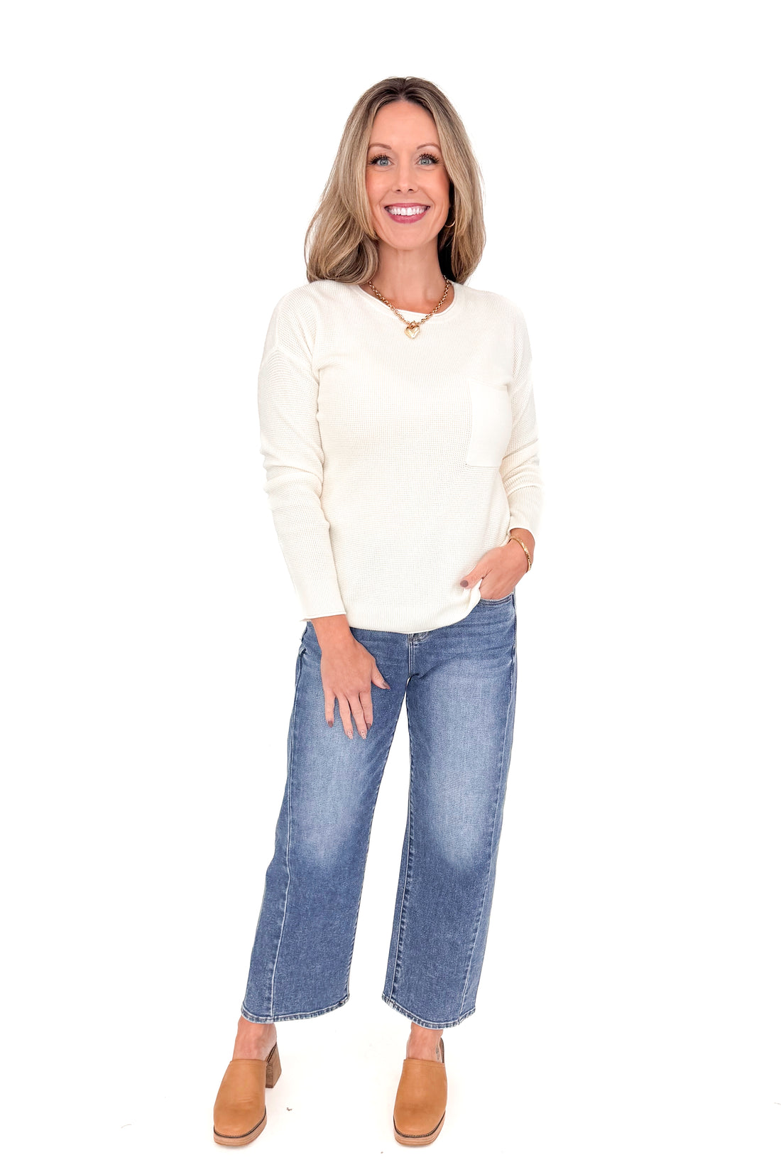 Front view of woman wearing Ivory Textured Pocket Detail Sweater with jeans against white studio background.