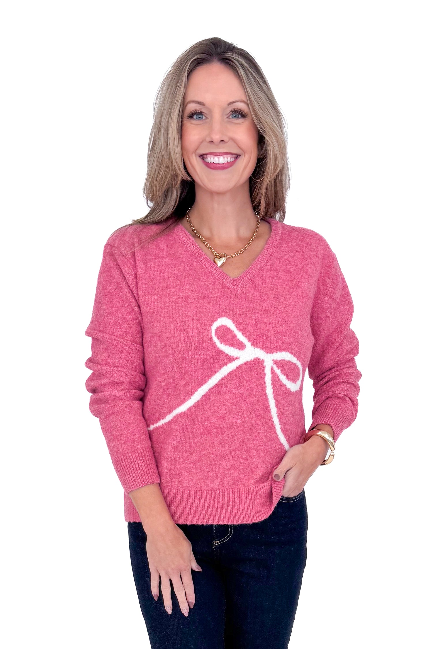 Front view of woman wearing Pink Bow Printed Sweater and blue jeans. 