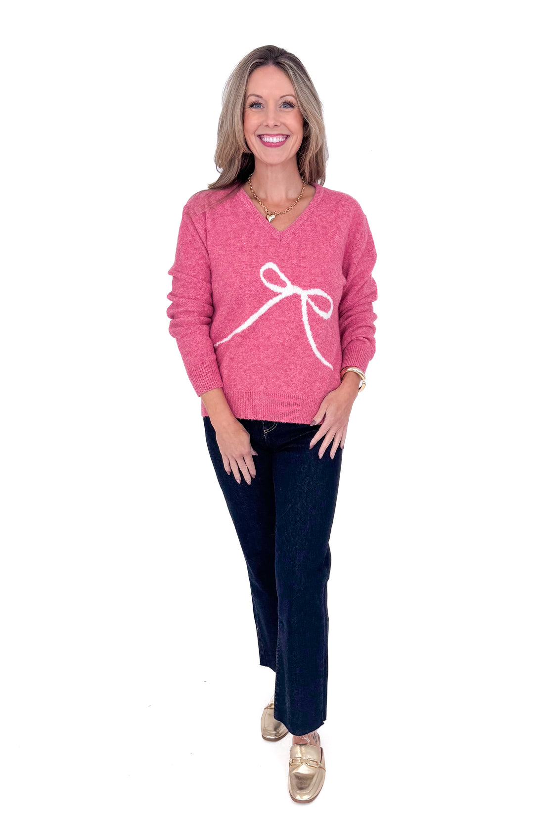 Front view of woman wearing Pink Bow Printed Sweater and blue jeans.