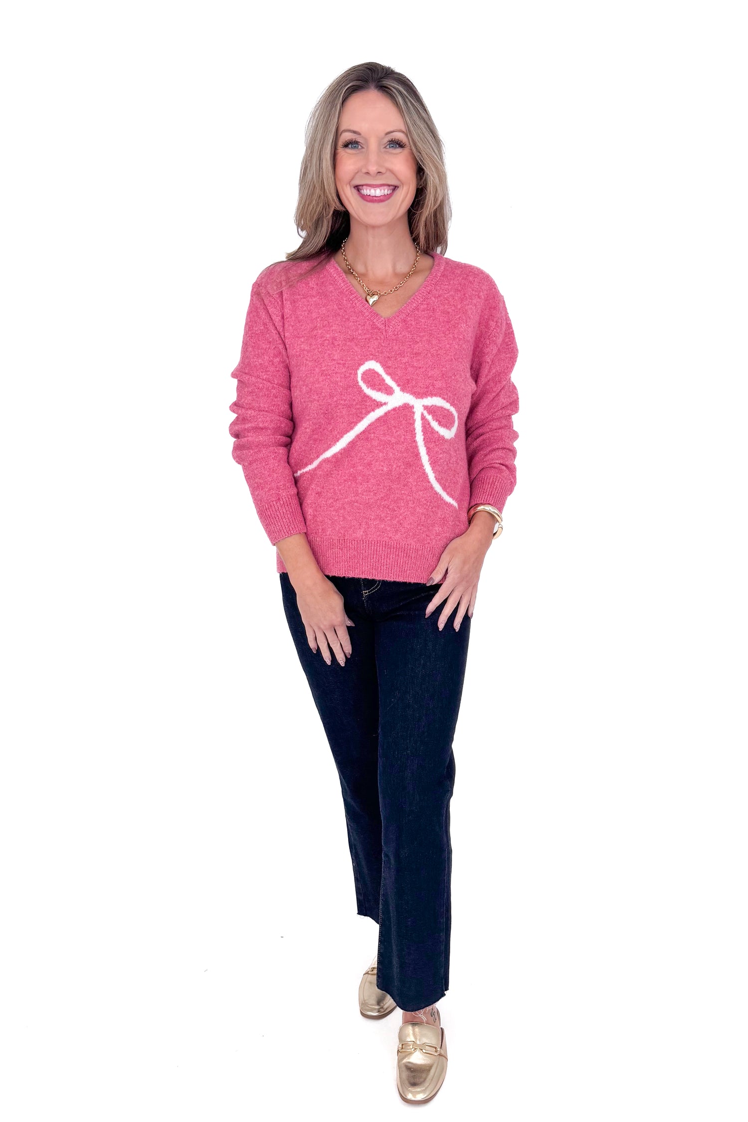 Front view of woman wearing Pink Bow Printed Sweater and blue jeans. 