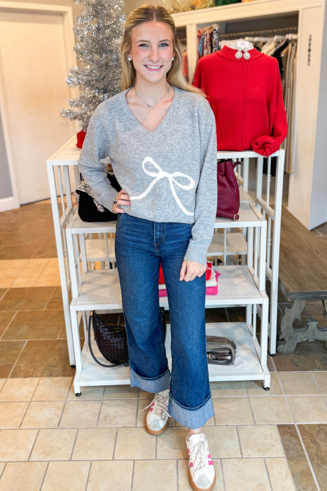 Front view of woman outdoor wearing Grey Bow Printed Sweater with jeans at a boutique
