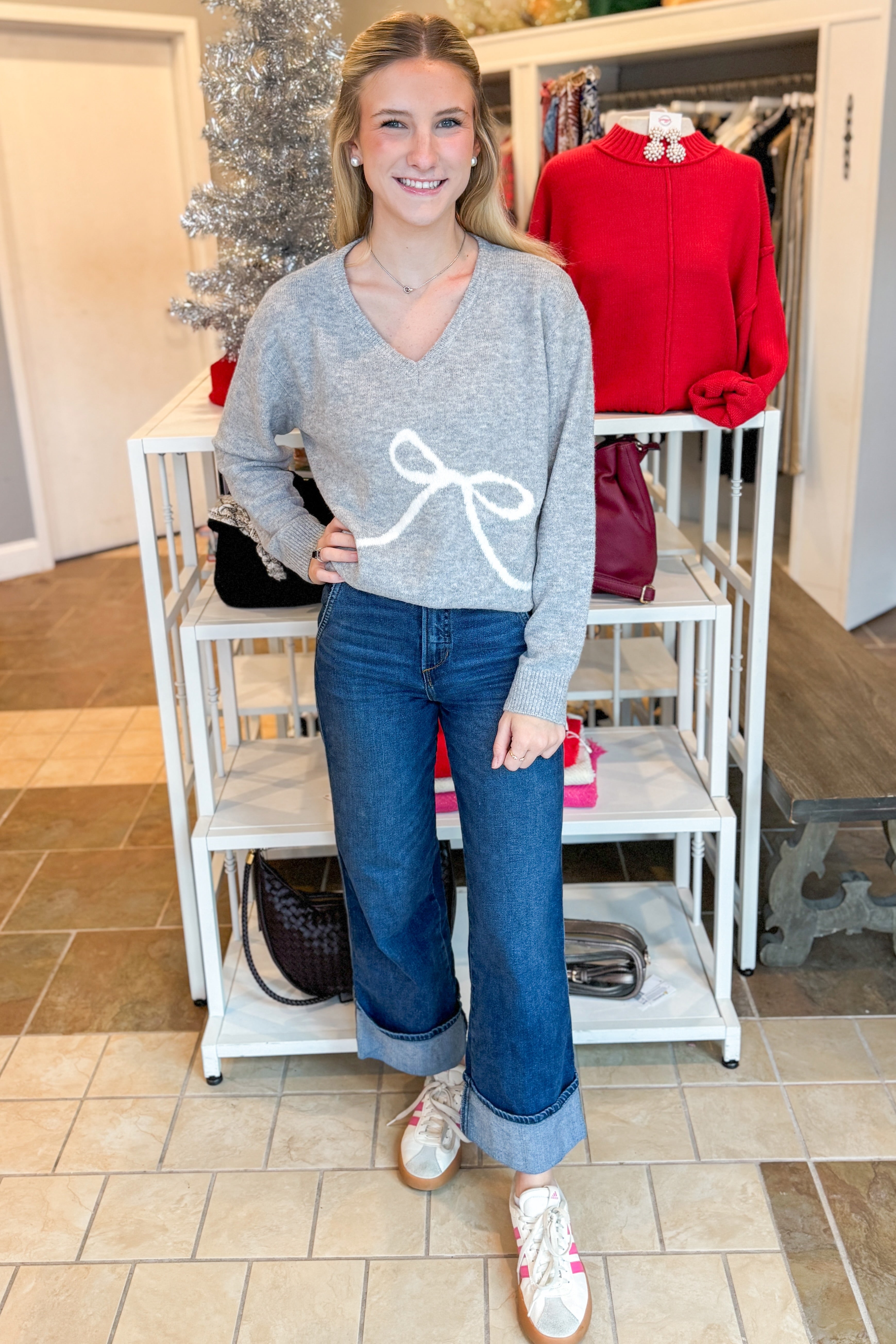 Front view of woman outdoor wearing Grey Bow Printed Sweater with jeans at a boutique