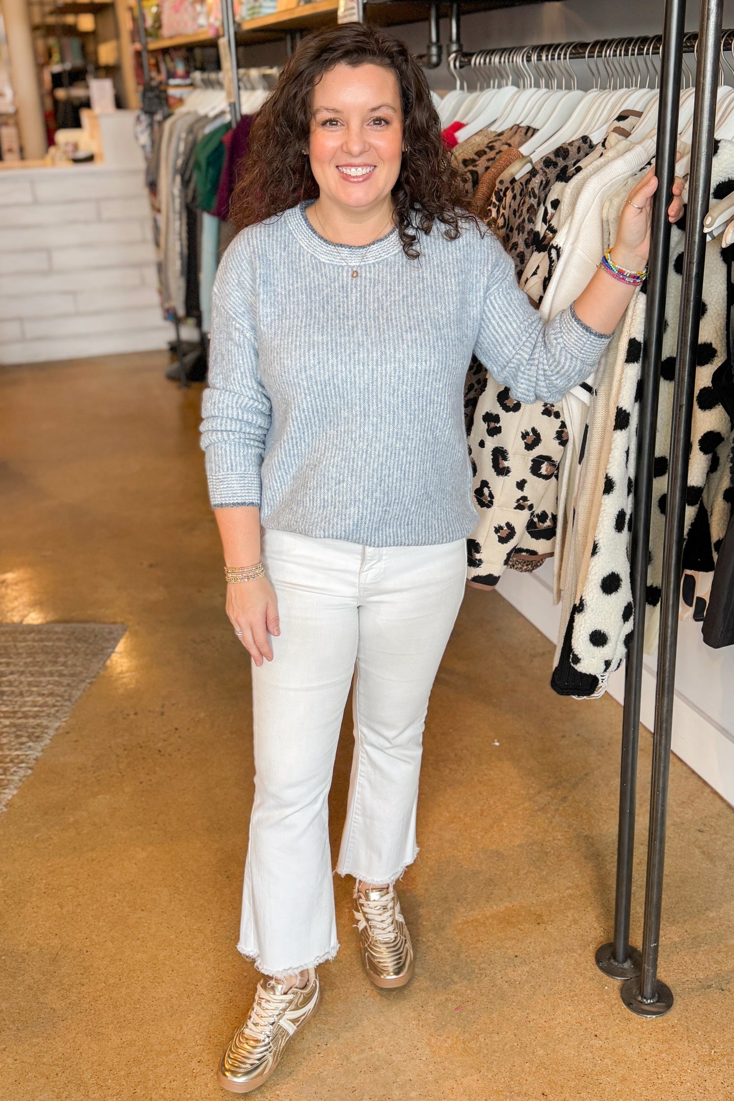 Front view of woman wearing Light Blue Ribbed Sweater with white jeans at a boutique.