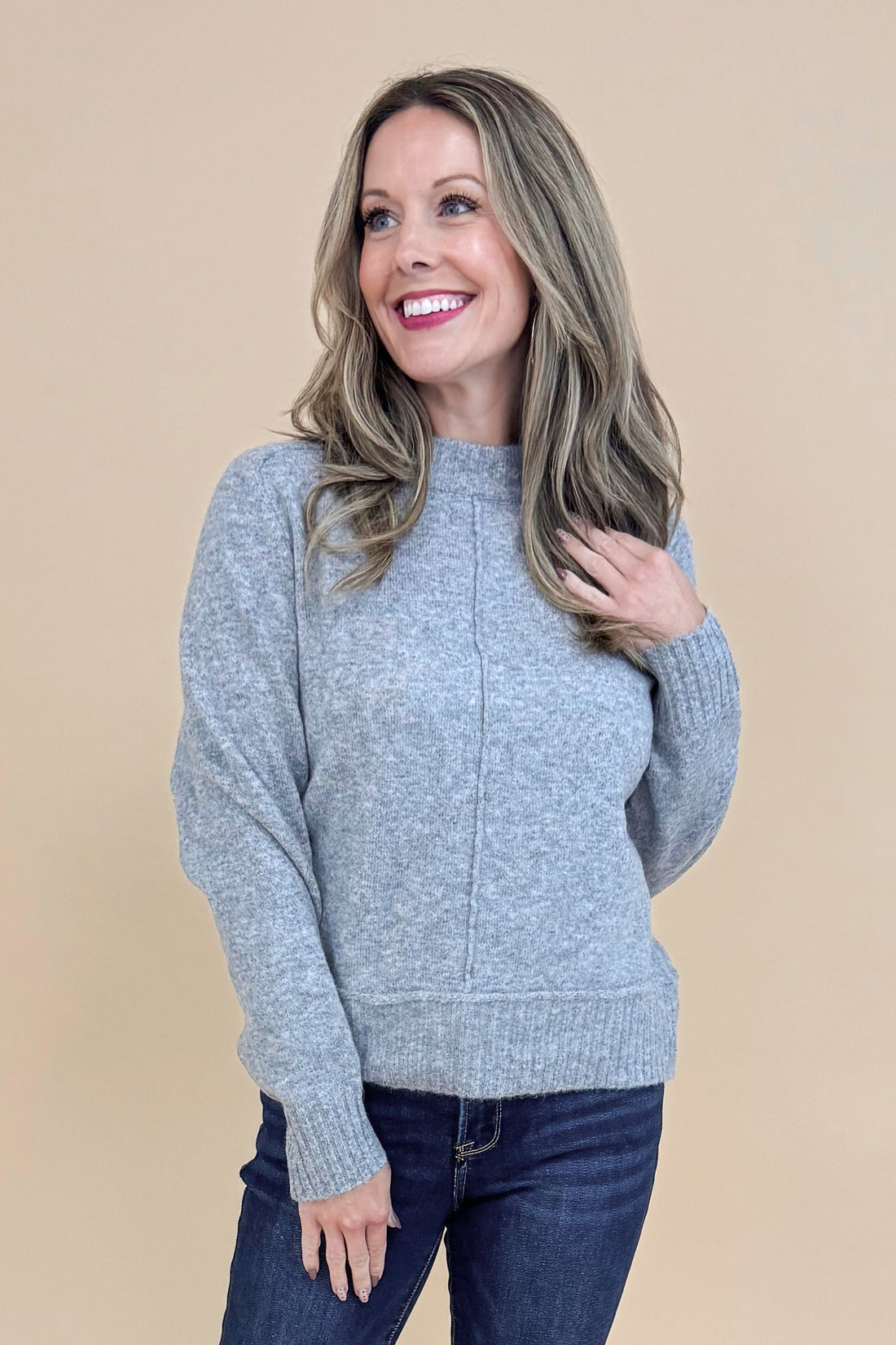 Front view of woman wearing Grey Center Seam Detail Sweater and blue jeans.