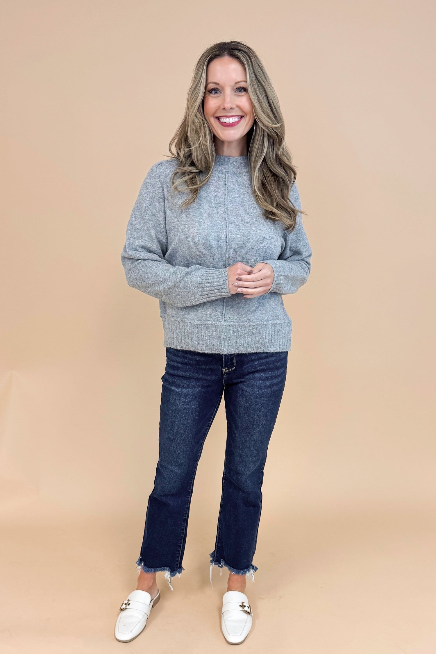 Front view of woman wearing Grey Center Seam Detail Sweater and blue jeans. 