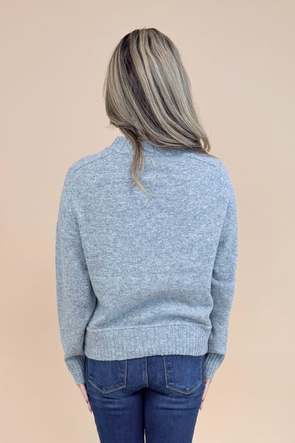 Back view of woman wearing Grey Center Seam Detail Sweater and blue jeans. 