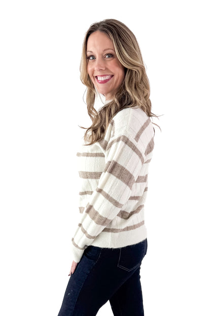 Side view of woman wearing Taupe and Cream Striped Mock Neck Sweater with jeans against white studio background.
