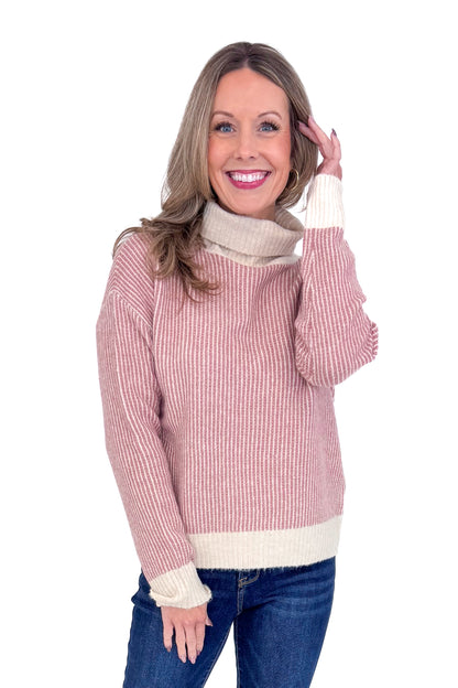 Front picture of woman wearing Mauve Striped Turtleneck Sweater and blue jeans against a white background.
