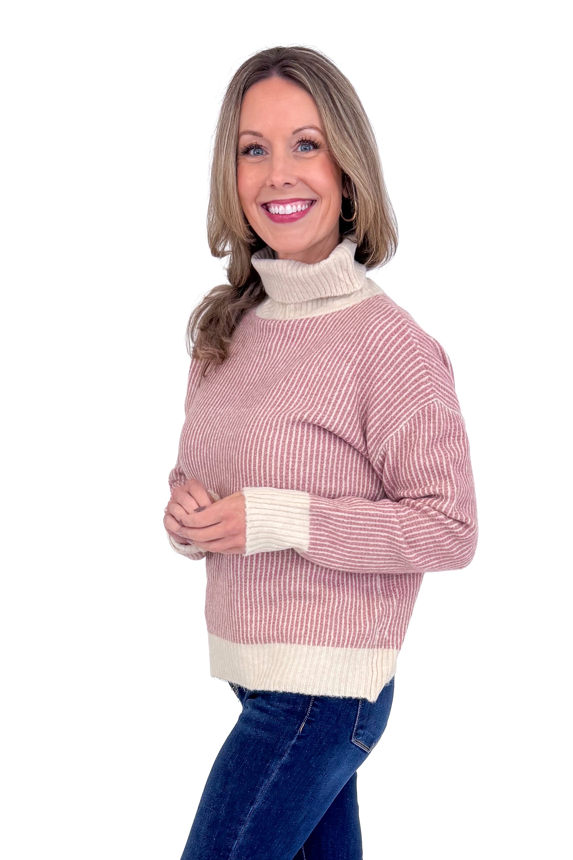Side picture of woman wearing Mauve Striped Turtleneck Sweater and blue jeans against a white background.