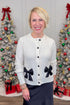 Front view of woman wearing Ivory Bow Pocket Detail Cardigan with jeans around holiday decor.