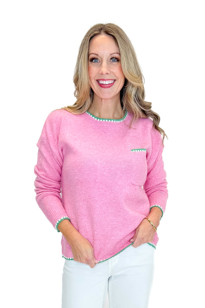 Front view of woman wearing Pink With Green Stitching Sweater with jeans against a white background.