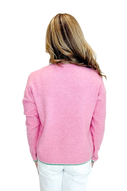 Back view of woman wearing Pink With Green Stitching Sweater with jeans against a white background.