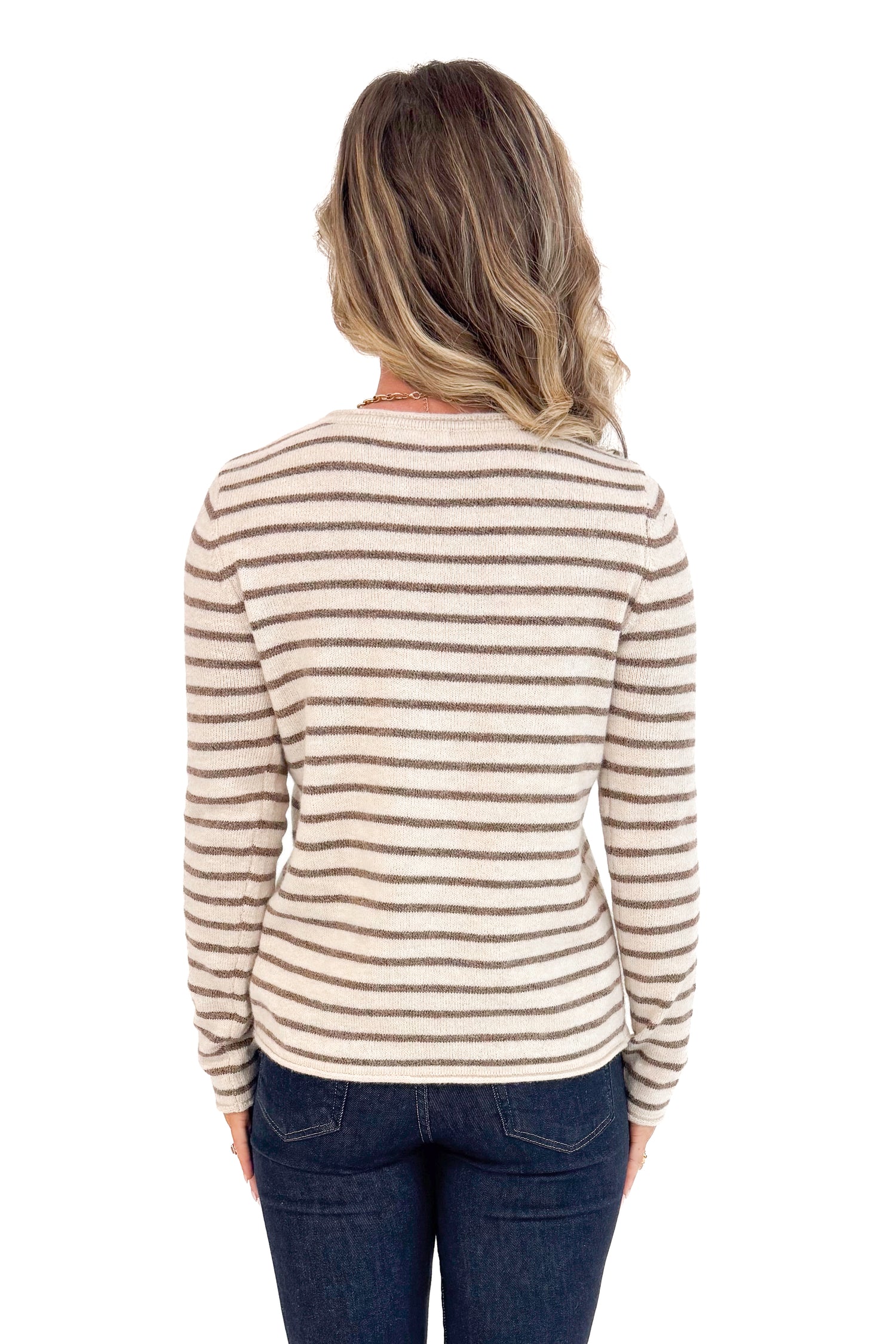 Back view of woman wearing Taupe and Brown Striped Sweater and jeans with white background.