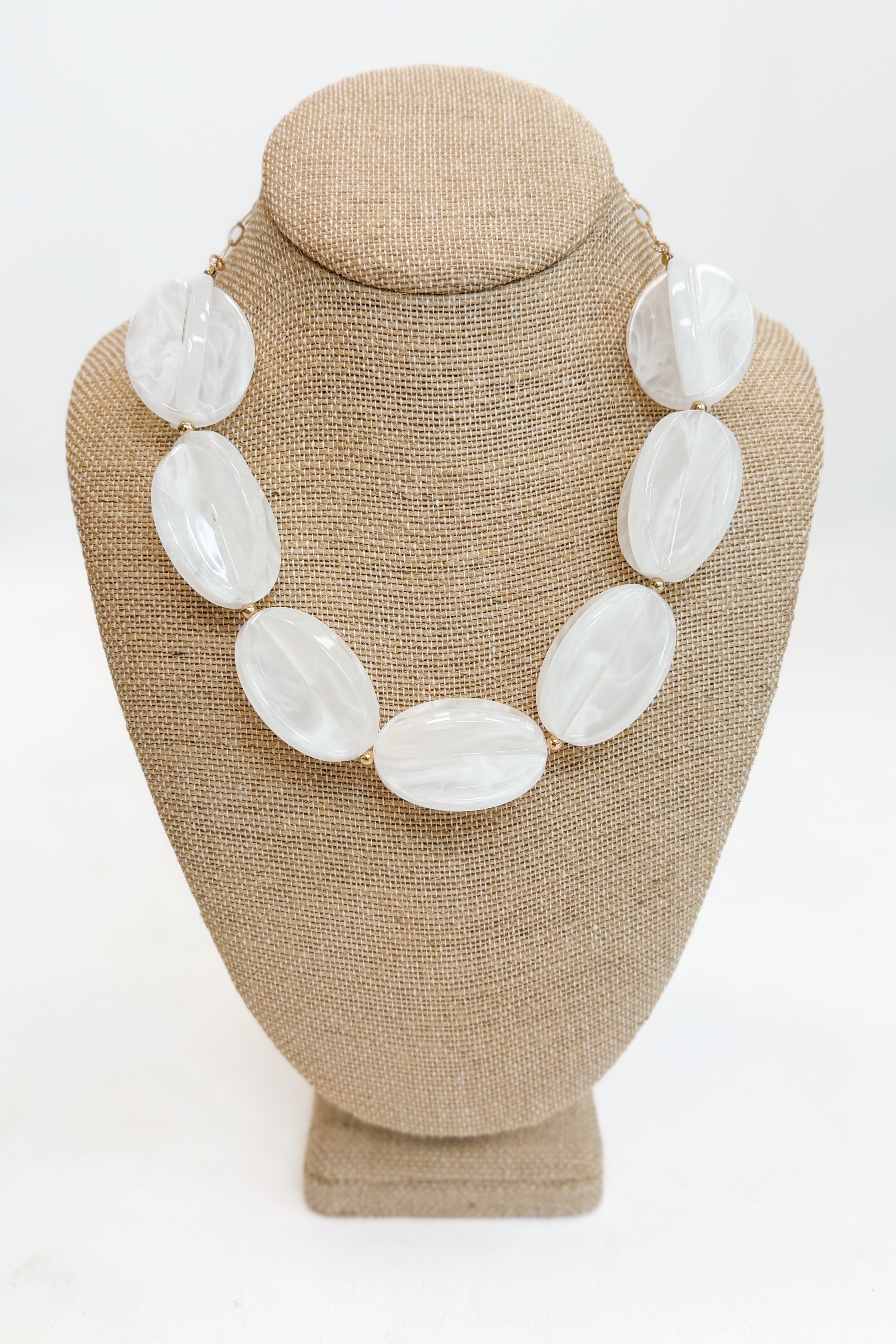 Necklace with large white beads on a beige mannequin bust against a white background