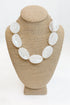 Necklace with large white beads on a beige mannequin bust against a white background