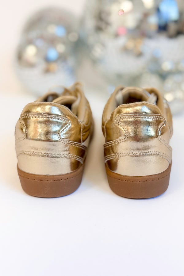 Pair of metallic gold shoes on a white background