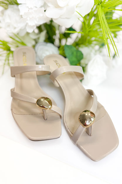 Beige high-heeled sandals with gold accents on a white background