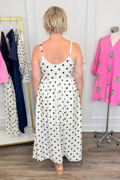 Back view of woman wearing Swagger Boutique’s Black &amp; Cream Polka Dot Layered Midi Dress by Entro with sandals at the store. 