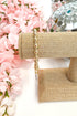 Gold bracelet on a jewelry stand with pink flowers in the background
