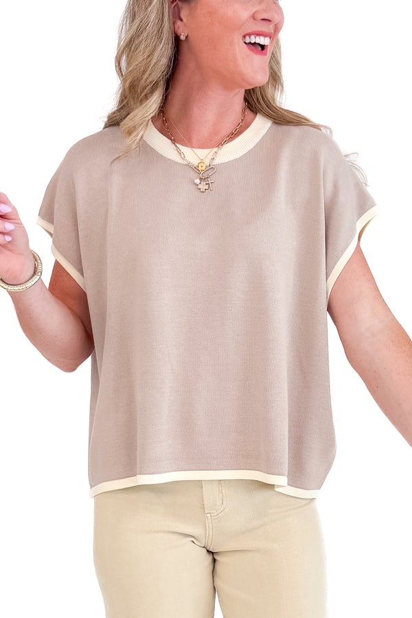 Woman wearing a beige blouse with a white collar and cuffs on a white background