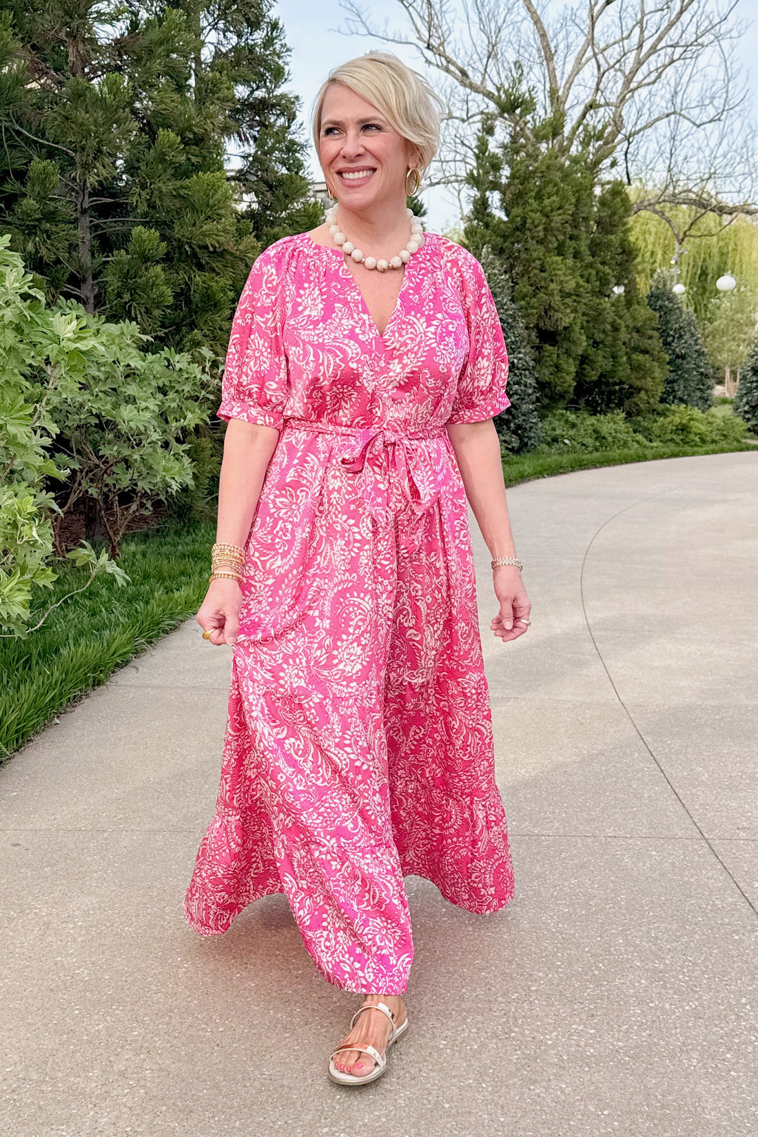 Front view of woman wearing Stop Right There Pink Floral &amp; Paisley Print Maxi Dress by PINCH with sandals outside at a park. 