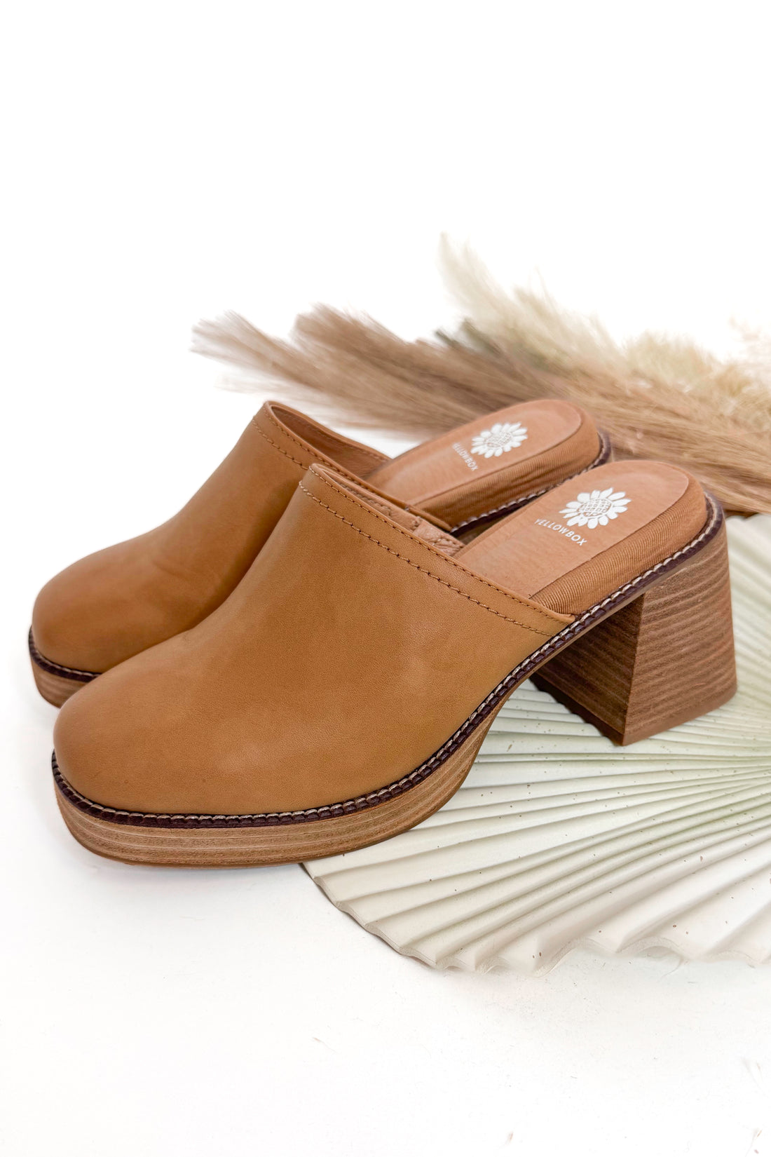 Pair of brown clogs with a wooden block heel on a white background