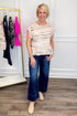 Front view of woman wearing Swagger Boutique’s Taupe, Brown & Blue Button Detail Sleeveless Sweater with jeans with clothing hanging in the background.