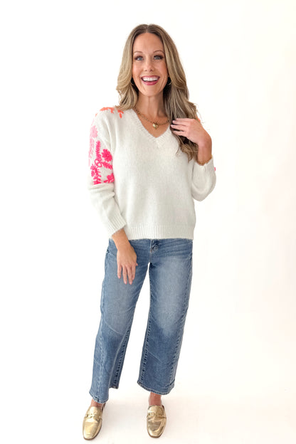 Front view of woman wearing Ivory With Floral Embroidery Sweater with jeans against white studio background.