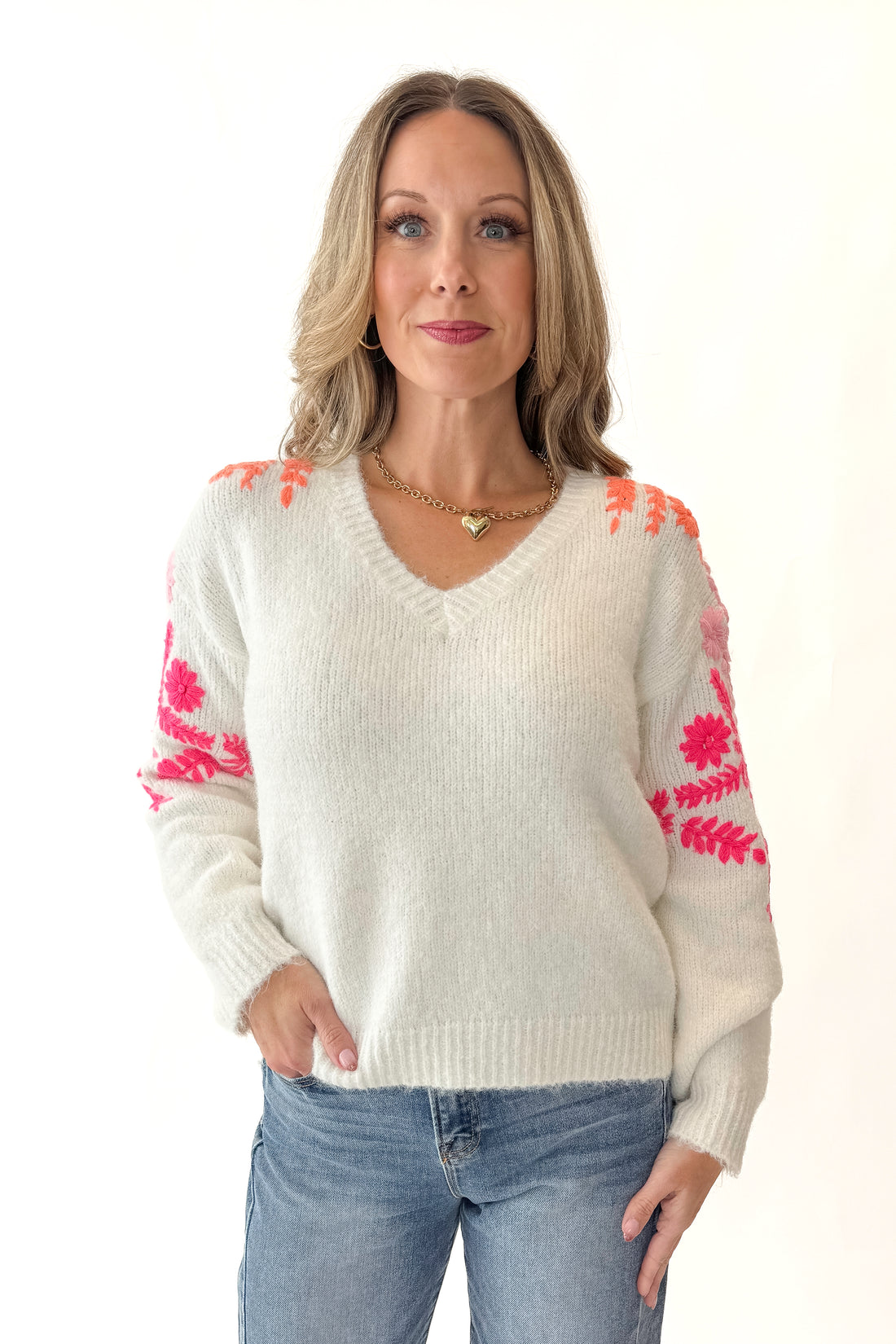 Front view of woman wearing Ivory With Floral Embroidery Sweater with jeans against white studio background.