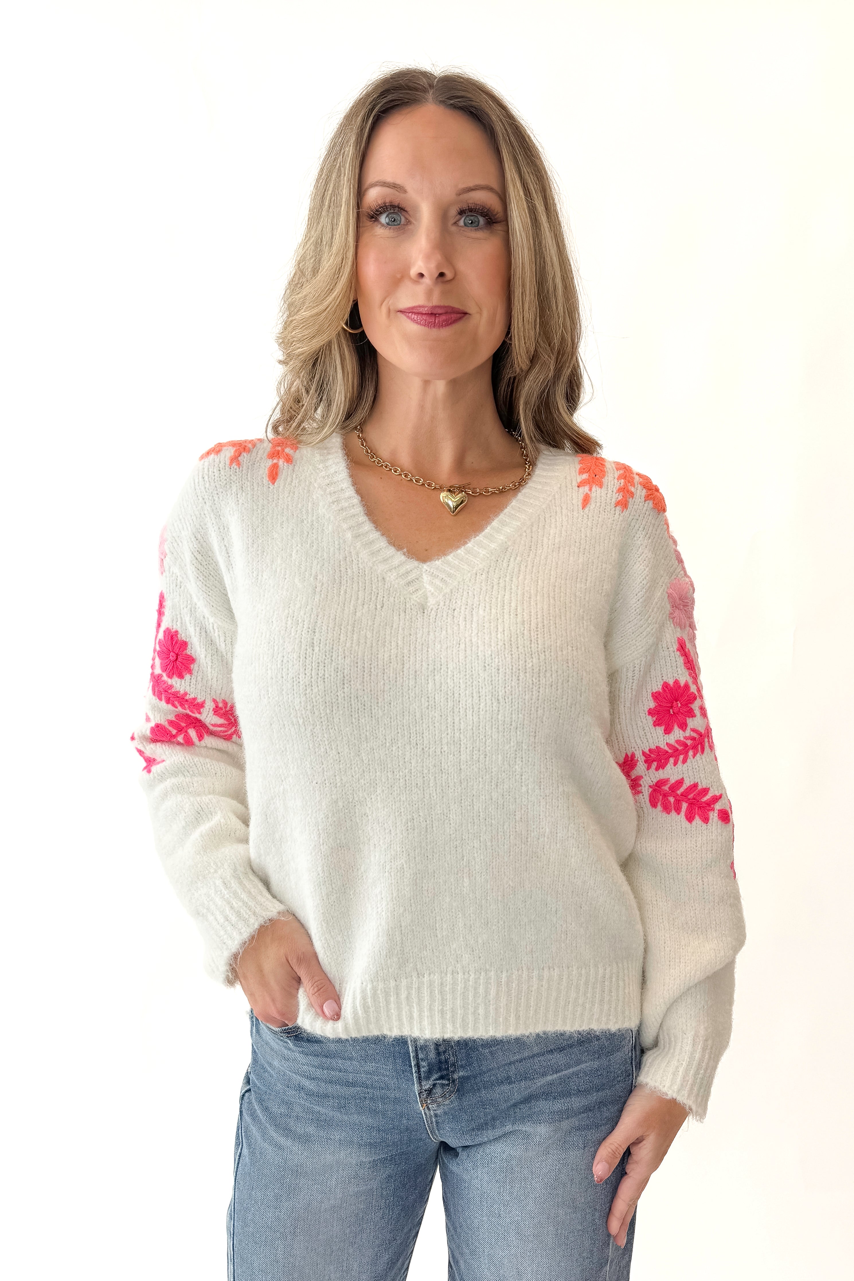 Front view of woman wearing Ivory With Floral Embroidery Sweater with jeans against white studio background.