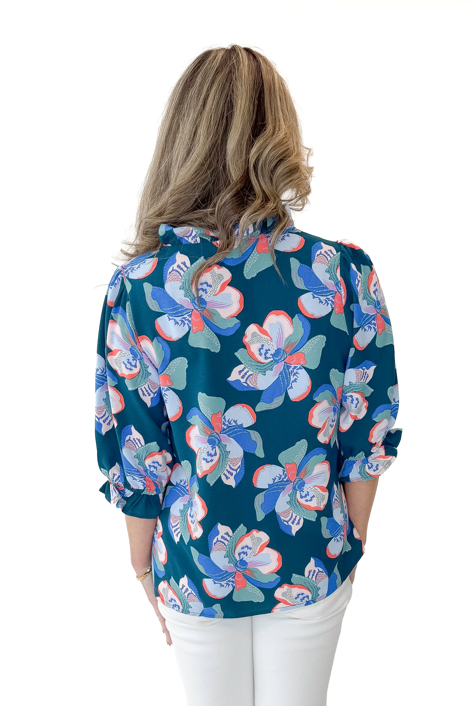 Back view of woman wearing Green &amp; Pink Floral Julie Top with jeans against white studio background.