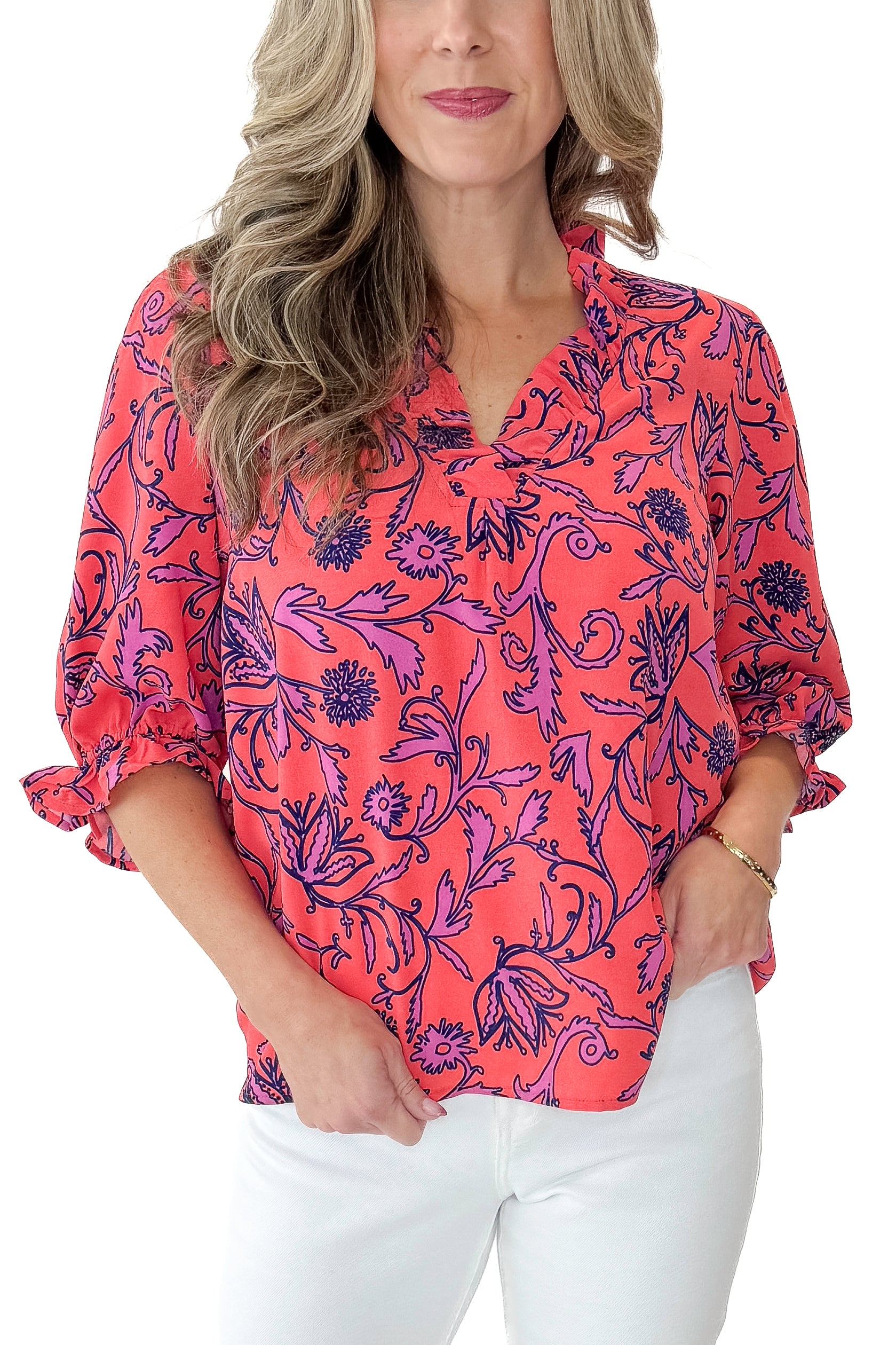 Front detail view of woman wearing Coral Printed Julie Top with jeans against white studio background.