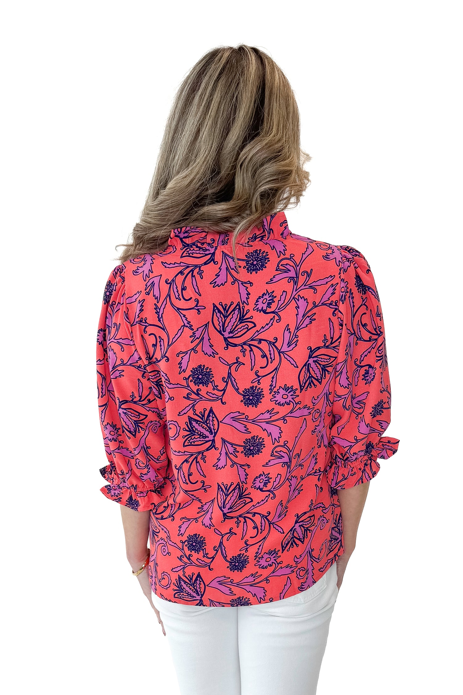 Back view of woman wearing Coral Printed Julie Top with jeans against white studio background.